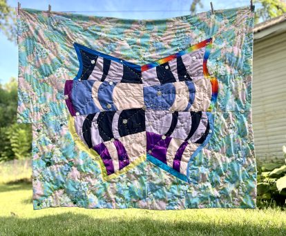 Sherri Lynn Wood, "Shimmer."  Abstract freestyle quilt, repurposed clothing, vintage sheets, wool yarn, buttons, glass beads, batting; hand-quilted
2024